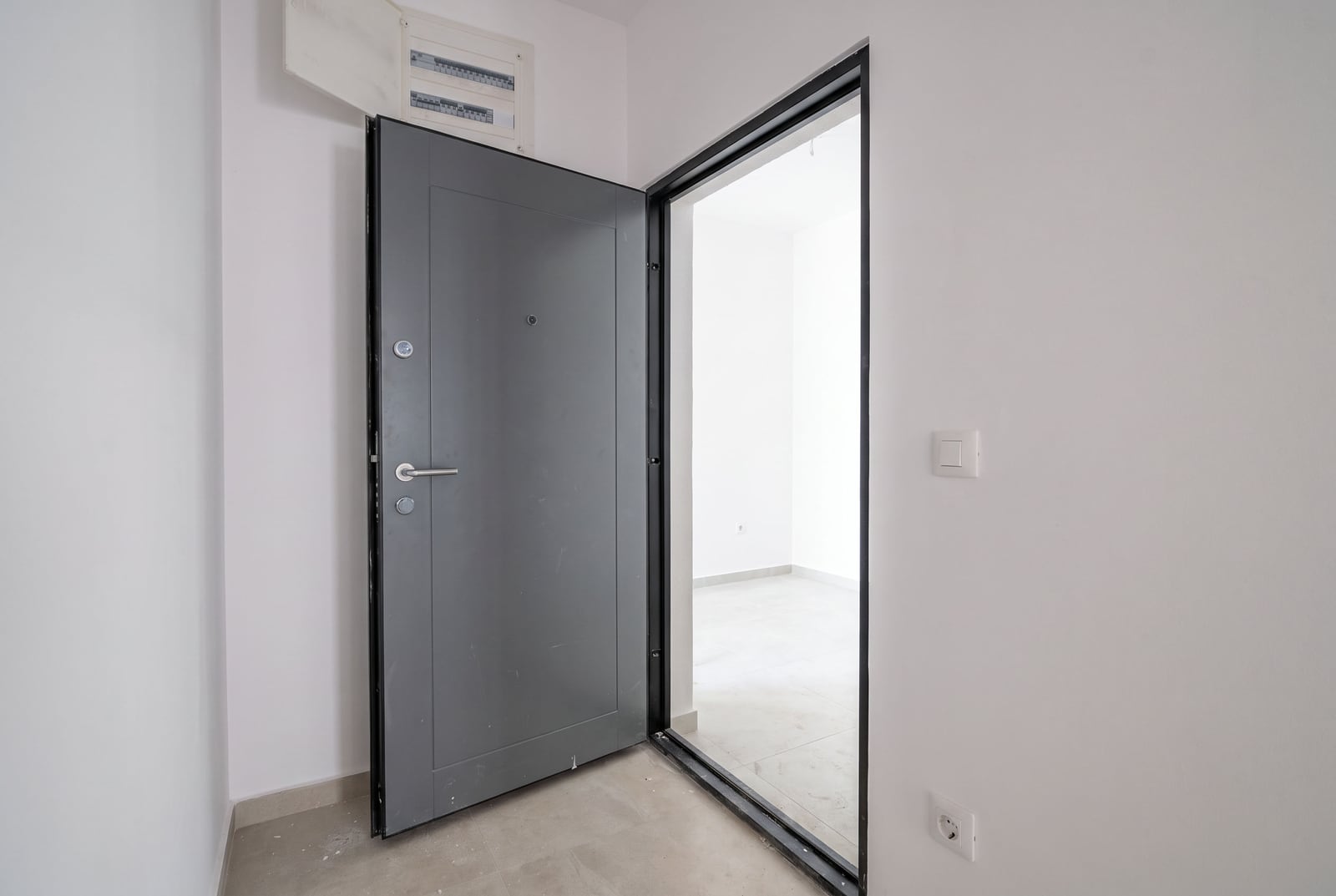Gray metal entrance door in a new apartment in the city of Bar, Montenegro, with finished finishes and a light interior.