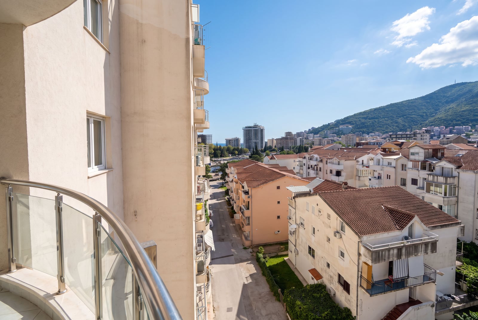 Pogled sa balkona stana u Budvi, Crna Gora: gradska izgradnja, krovovi od crijepa i planine