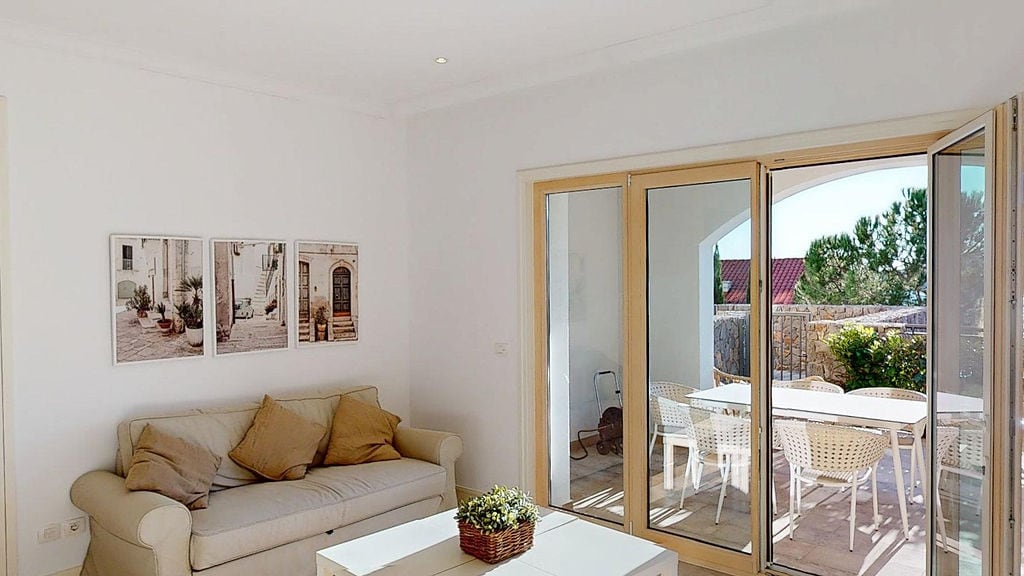 Helles Wohnzimmer mit Zugang zur Terrasse in einer Wohnung, Luštica, Montenegro: beiges Sofa, Panoramafenster und Blick auf den Garten.