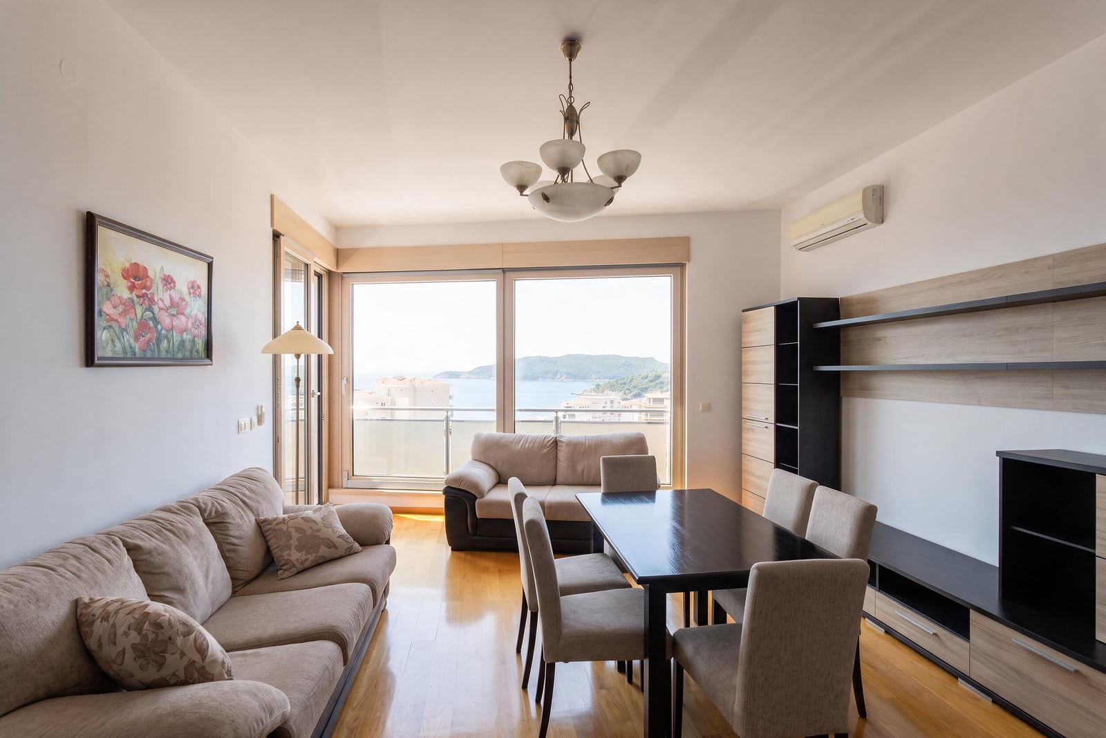 Spacious living room with furniture, dining area, and panoramic sea view in an apartment in Bečići, Montenegro.