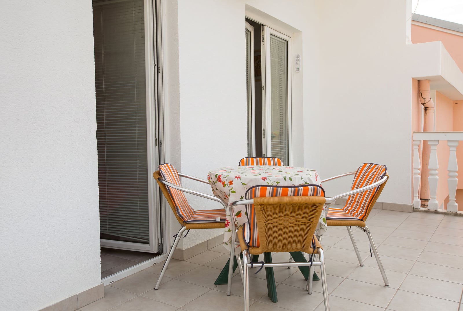 White terrace with tile flooring, a round table, and wicker chairs in an apartment in Budva, Montenegro