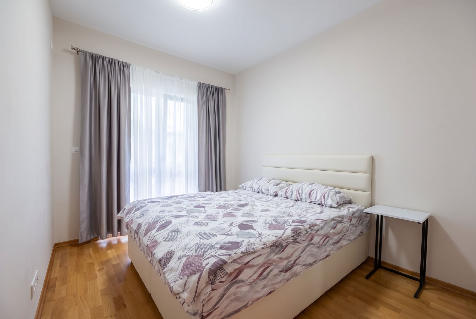 Svetla spavaća soba sa bračnim krevetom i parketom u stanu u Budvi, Crna Gora