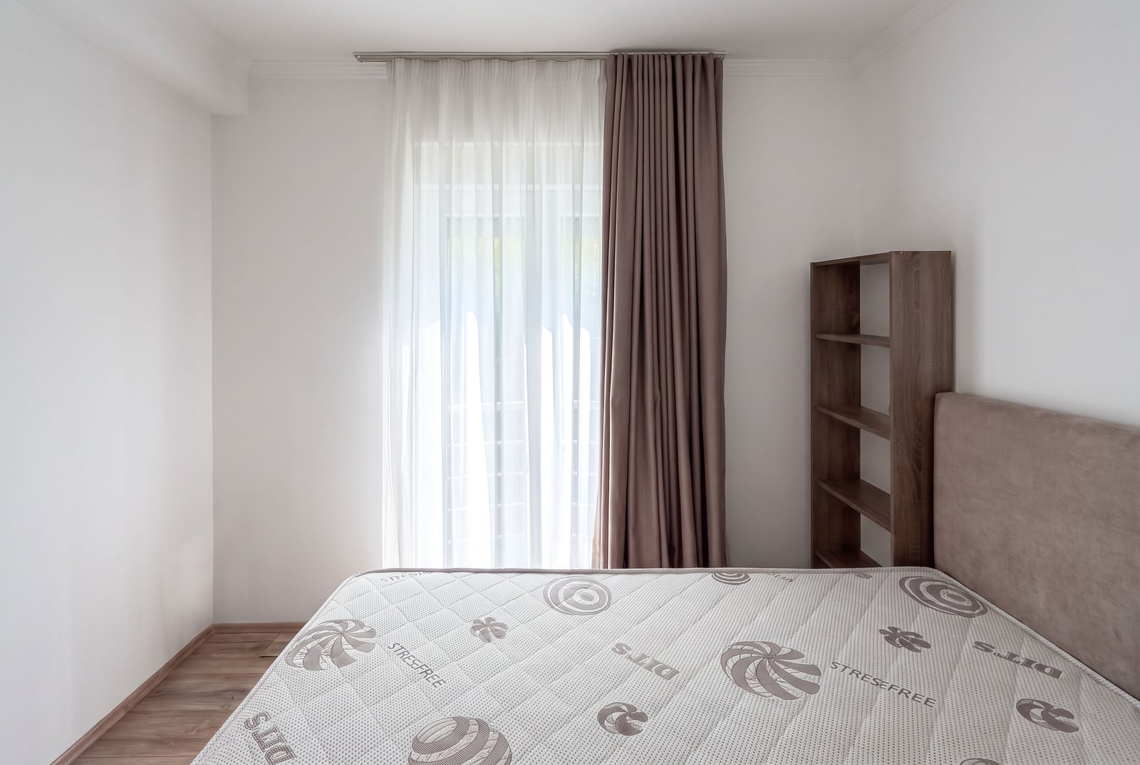 Svetla spavaća soba sa krevetom, ormanom i prozorom sa debelim zavesama u stanu u Tivtu, Crna Gora