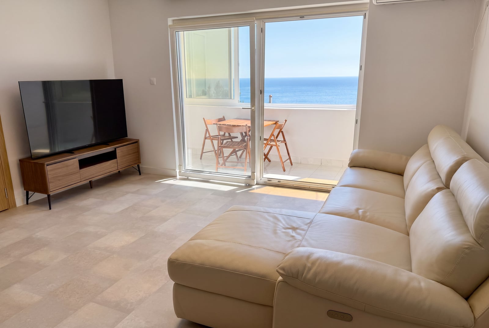Living room with a leather sofa and sea view in an apartment, Sveti Stefan, Montenegro: terrace with furniture and a TV area.