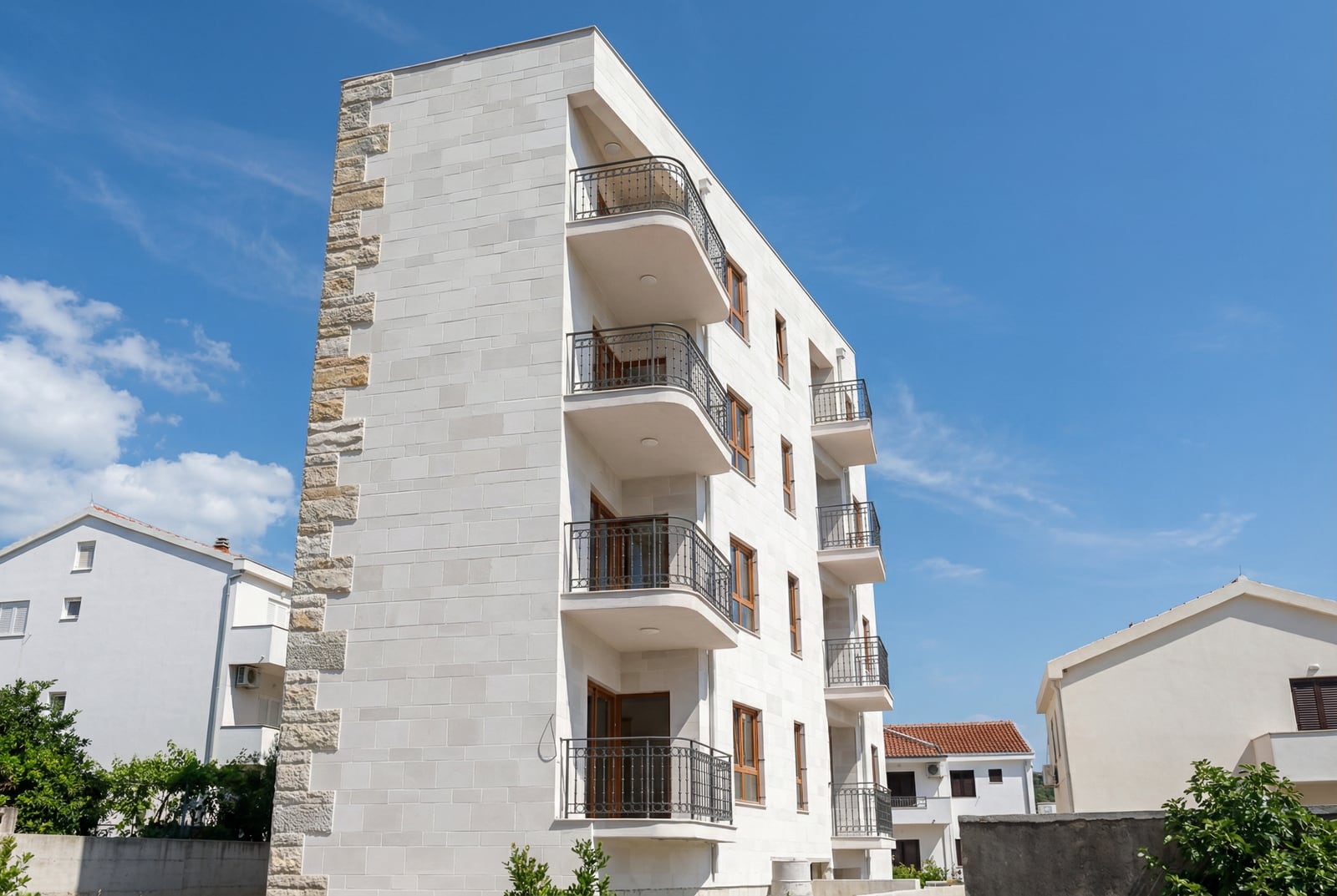 Modern residential building with stone facade cladding and balconies in Petrovac, Montenegro.