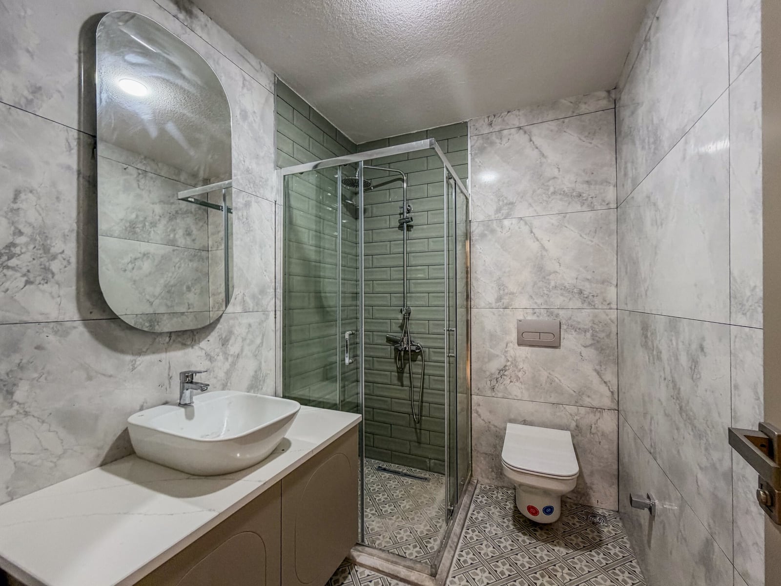 Modern bathroom with a shower cabin, sink, and wall-hung toilet in an apartment in Budva, Montenegro