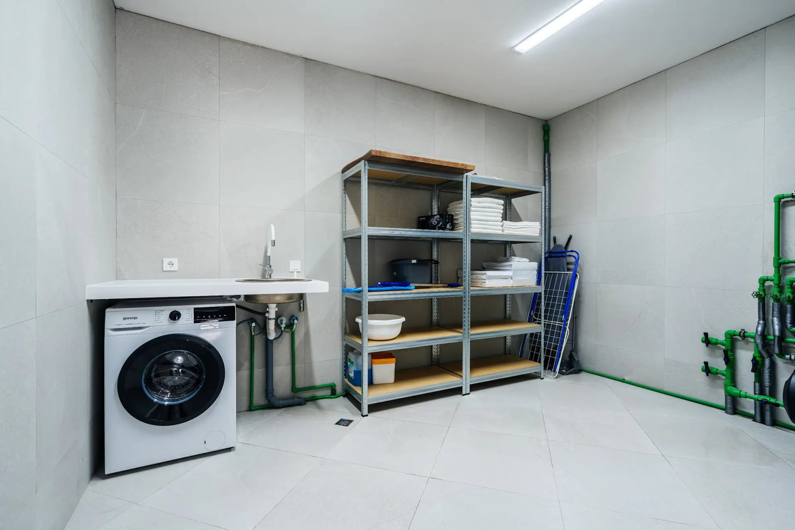Utility room with laundry area and shelving in a villa in Reževići, Montenegro: washing machine and storage space.