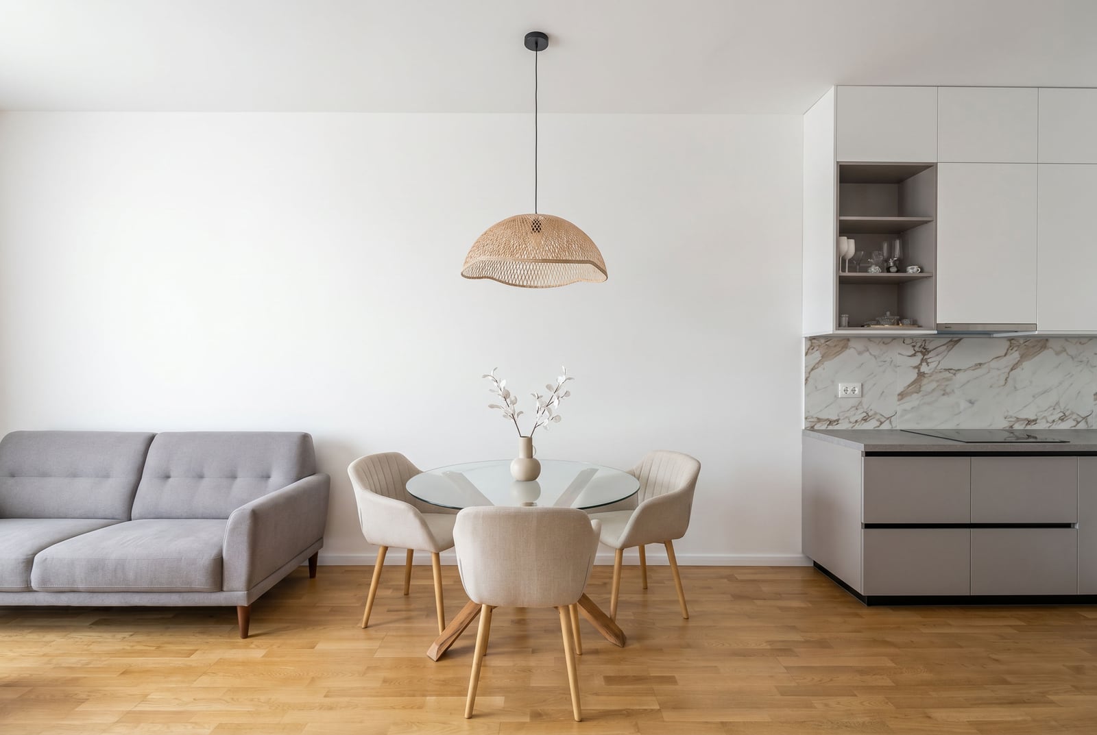 Moderna dnevna soba sa kuhinjom u stanu u Bečićima, Crna Gora: siva sofa, trpezarija i moderan enterijer.