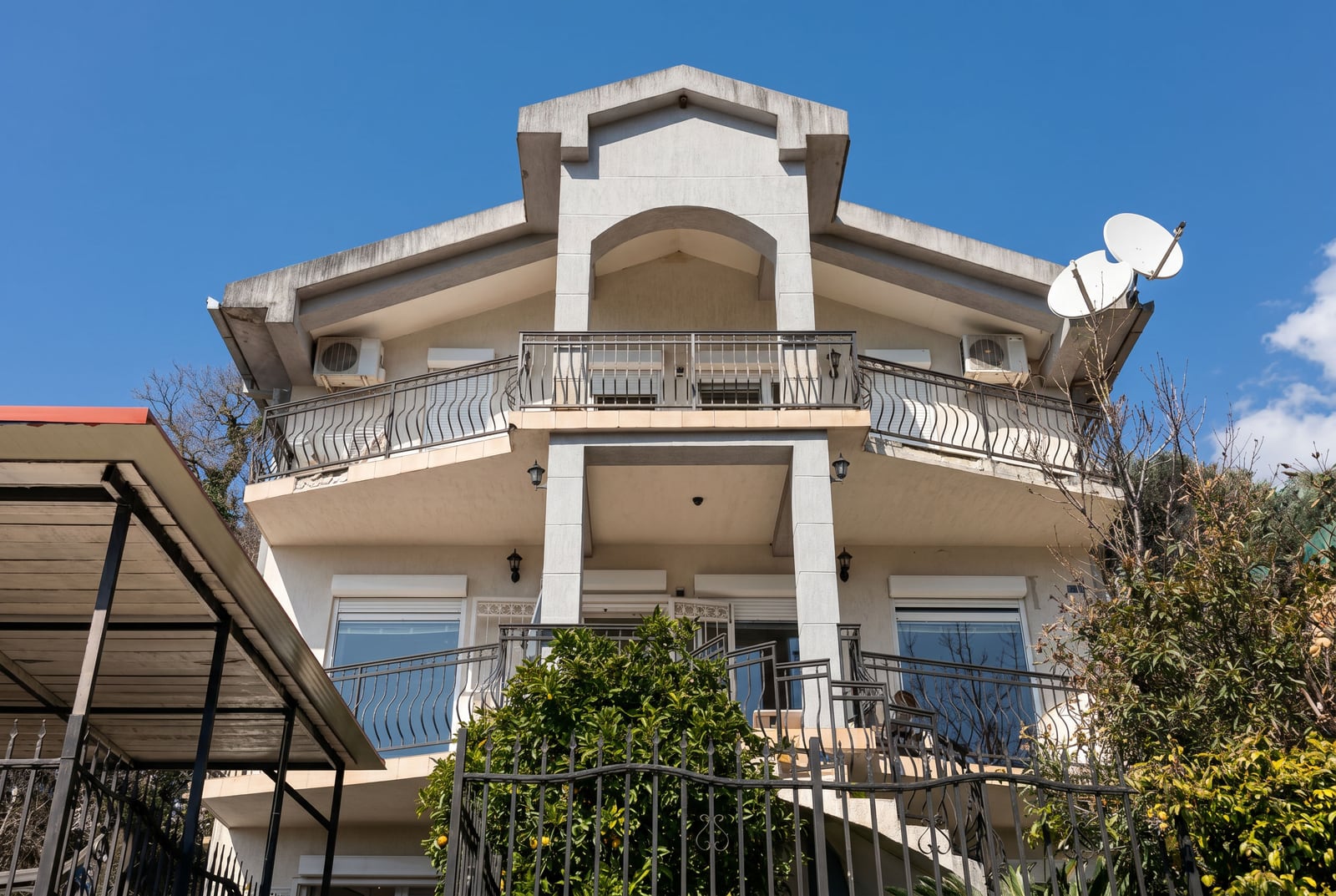 Three-story private house with balconies and a terrace in Buljarica, Montenegro: view of the building facade with wrought-iron railings.